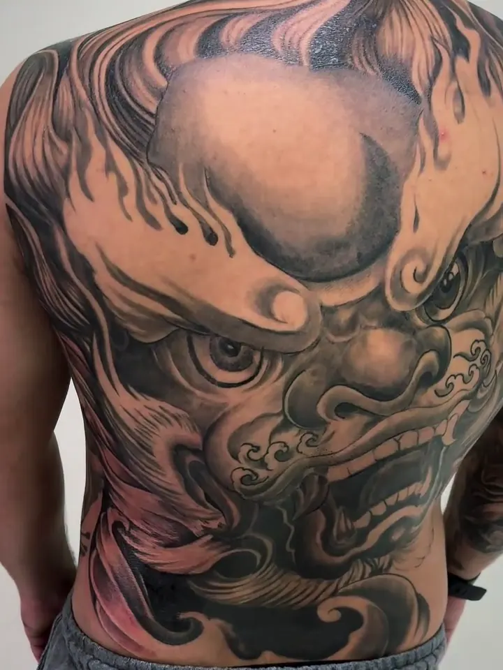 Costas inteiras com um Fu Dog em preto e cinza, entre chamas e ondas